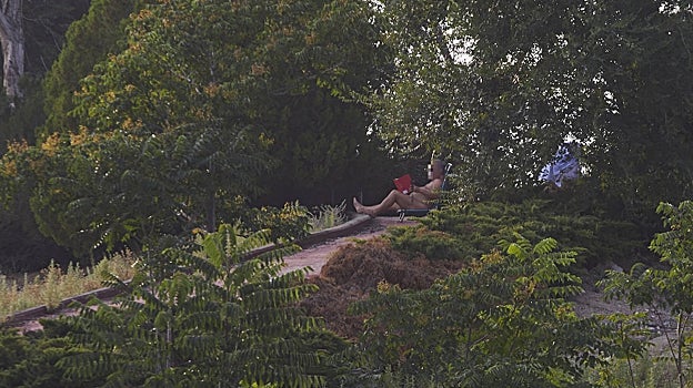 Un hombre lee un libro desnudo en la parte alta del recinto, donde antes nacían los toboganes desmantelados