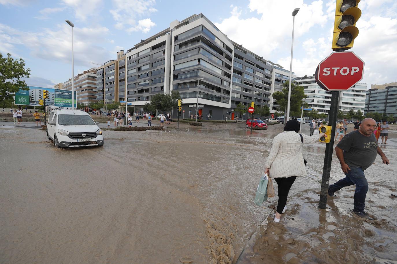 Vehículos tratan de circular por las calles anegadas de Zaragoza tras la tromba.