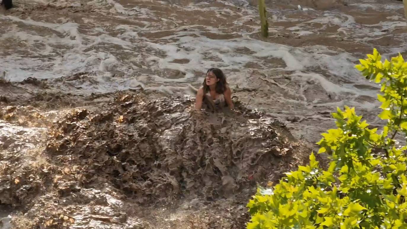 Una mujer resiste sobre el techo de un coche a la tormenta