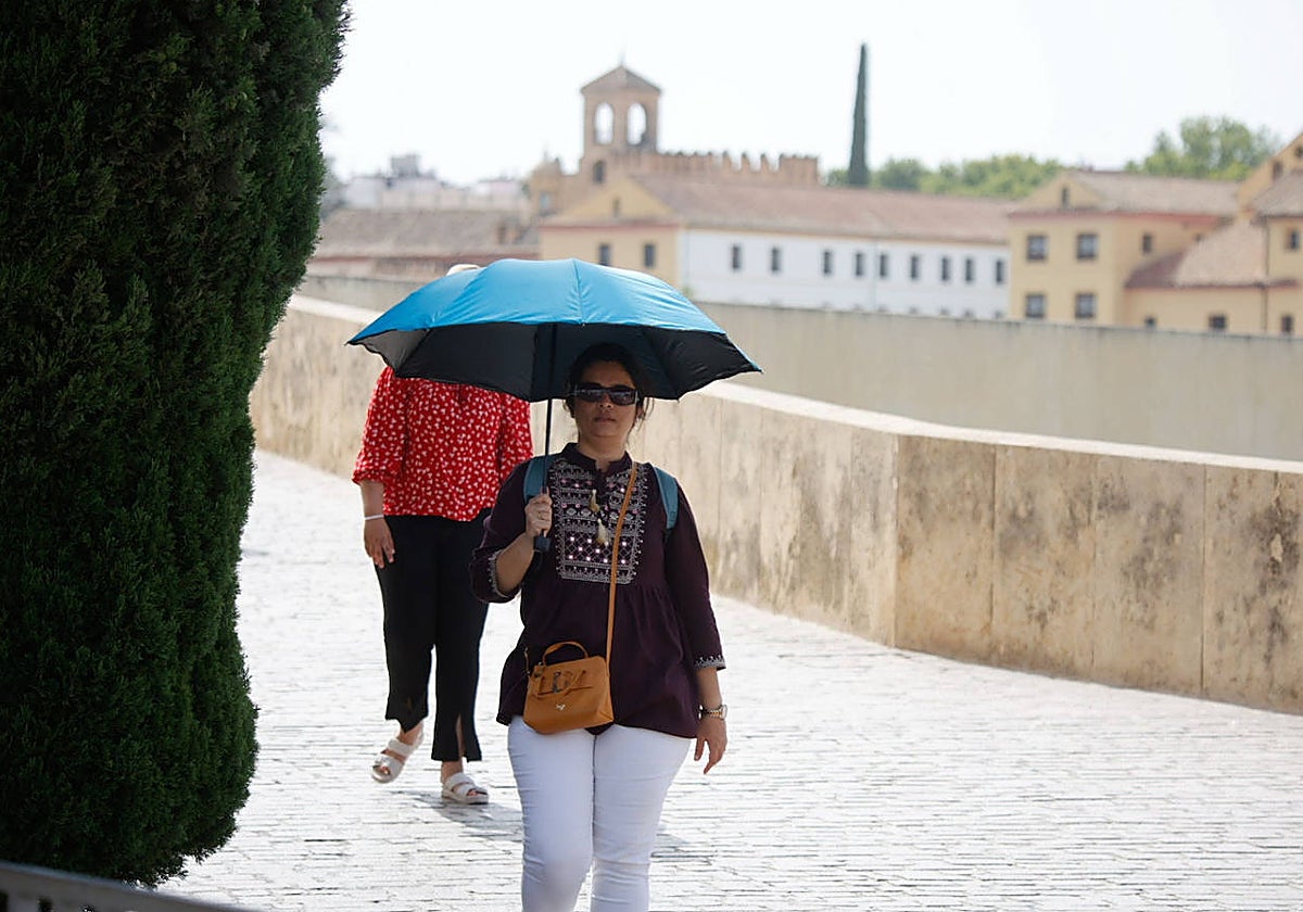 Una mujer se protege del calor en el Puente Romano de Córdoba