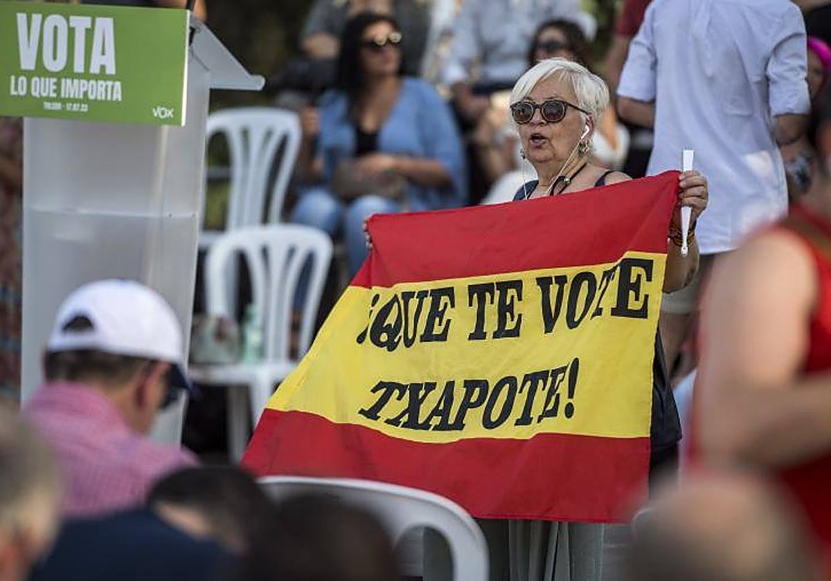 Una mujer participa en un mitin de Vox con una bandera con el lema 'Que te vote Txapote'