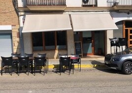 Un bar monta dos mesas de su terraza encima de un coche aparcado junto a la acera
