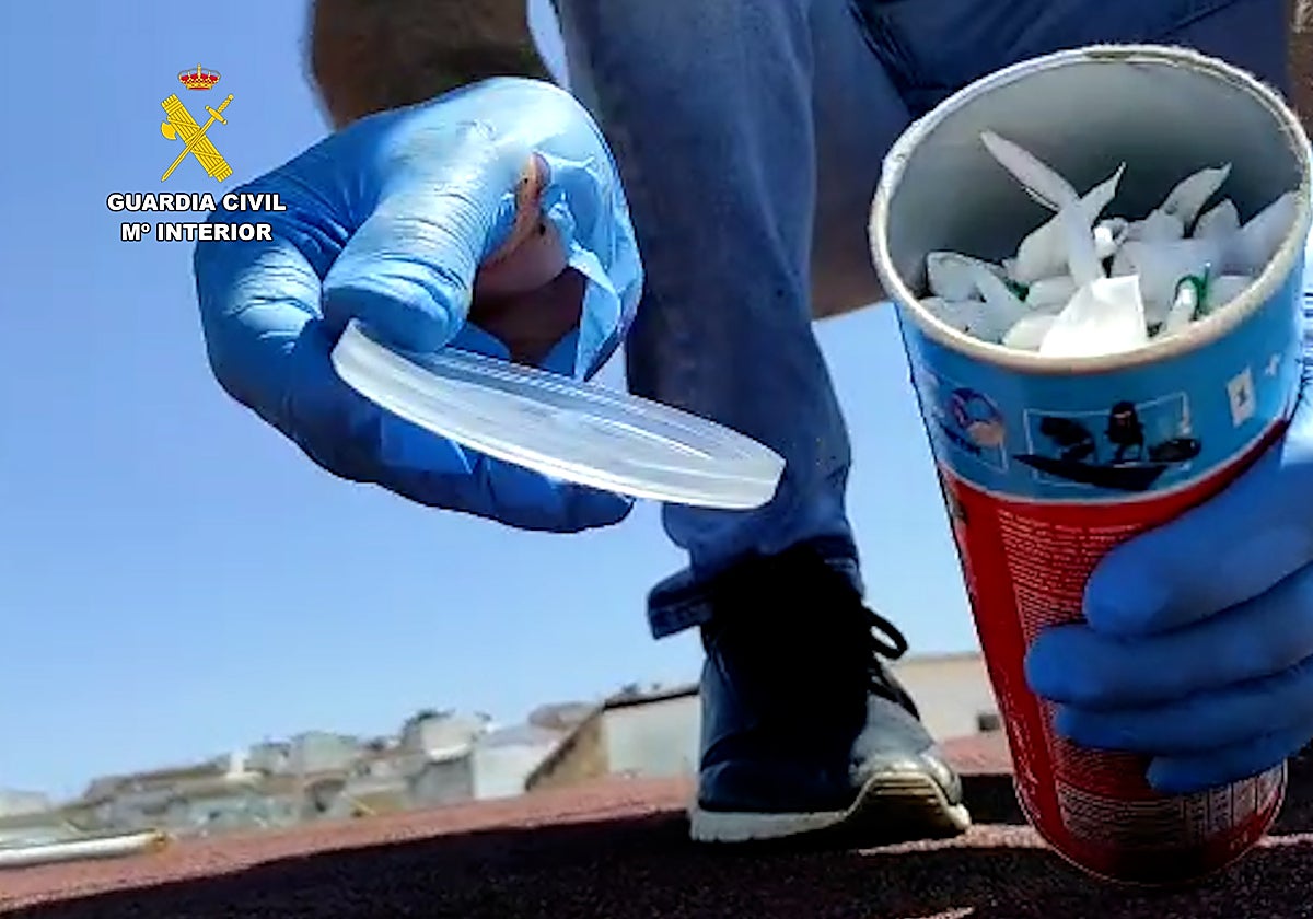 Un agente muestra un bote en cuyo interior hay bolsitas de droga incautada