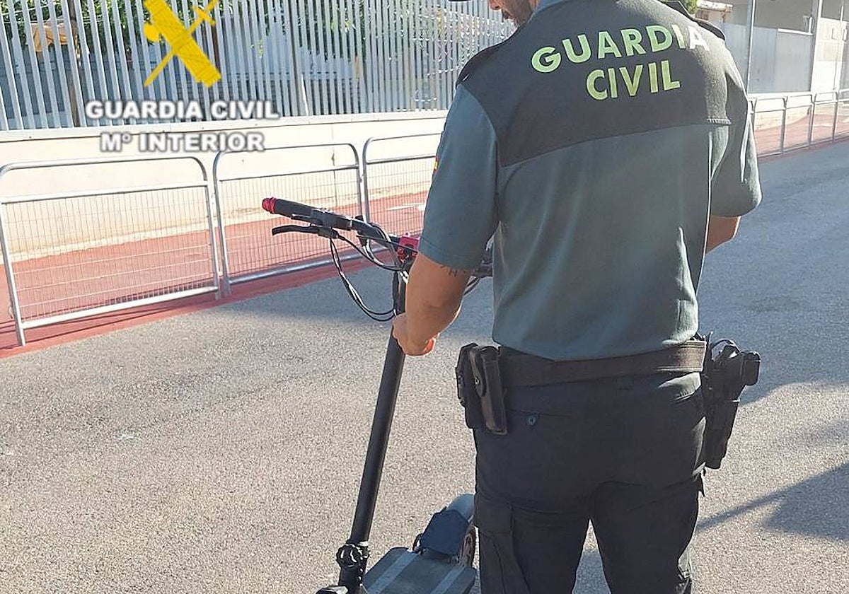 Imagen de un agente de Guardia Civil de Benicasim con el patinete eléctrico recuperado