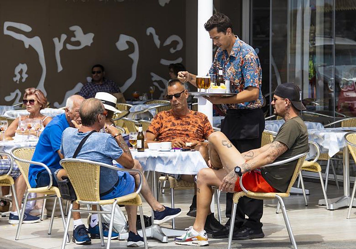 Un camarero sirve consumiciones a los clientes de un bar en Benidorm