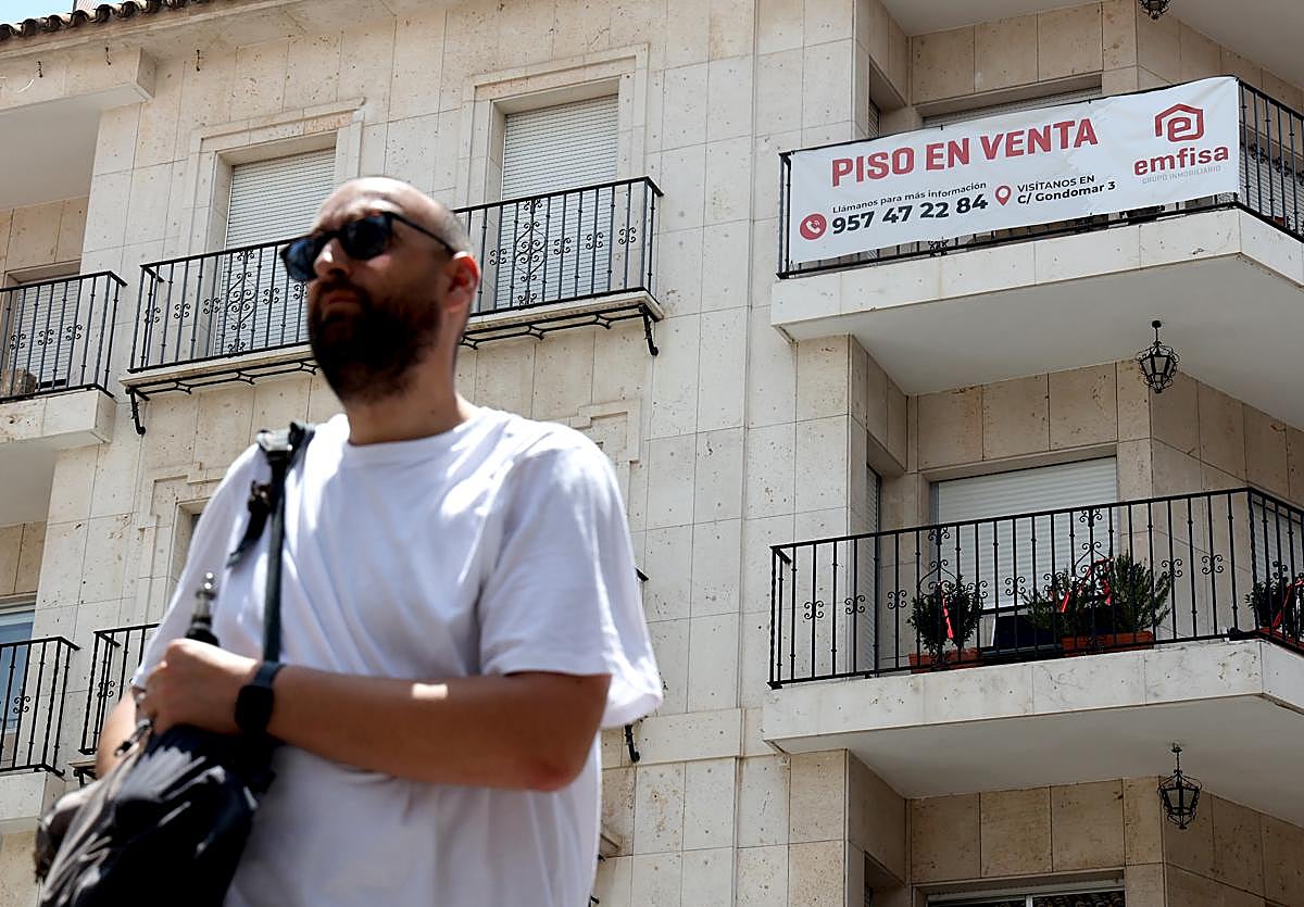 Un hombre pasa delante de un edificio con una vivienda en venta
