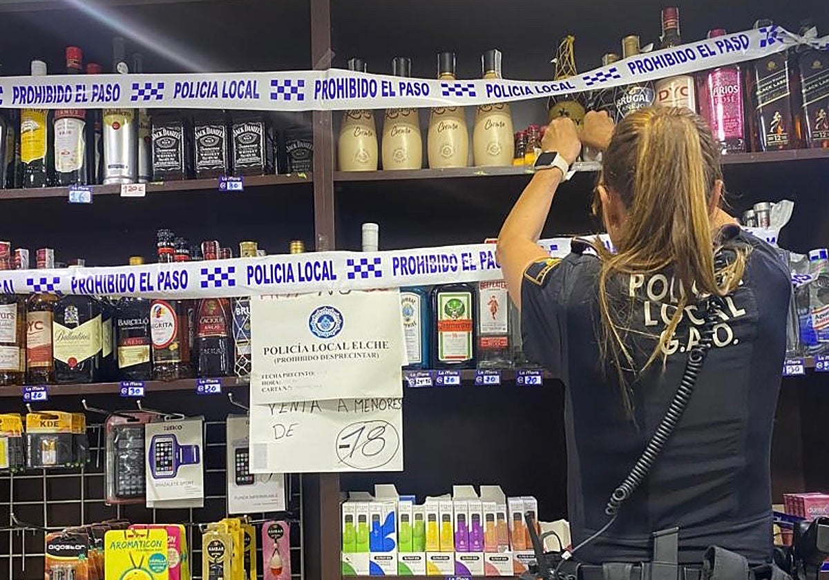 Una agente de la Policía Local de Elche precinta botellas de alcohol de venta ilegal a menores durante las fiestas.