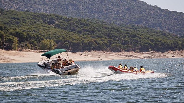 Una embarcación de ocio realiza maniobras con un hinchable detrás en el pantano