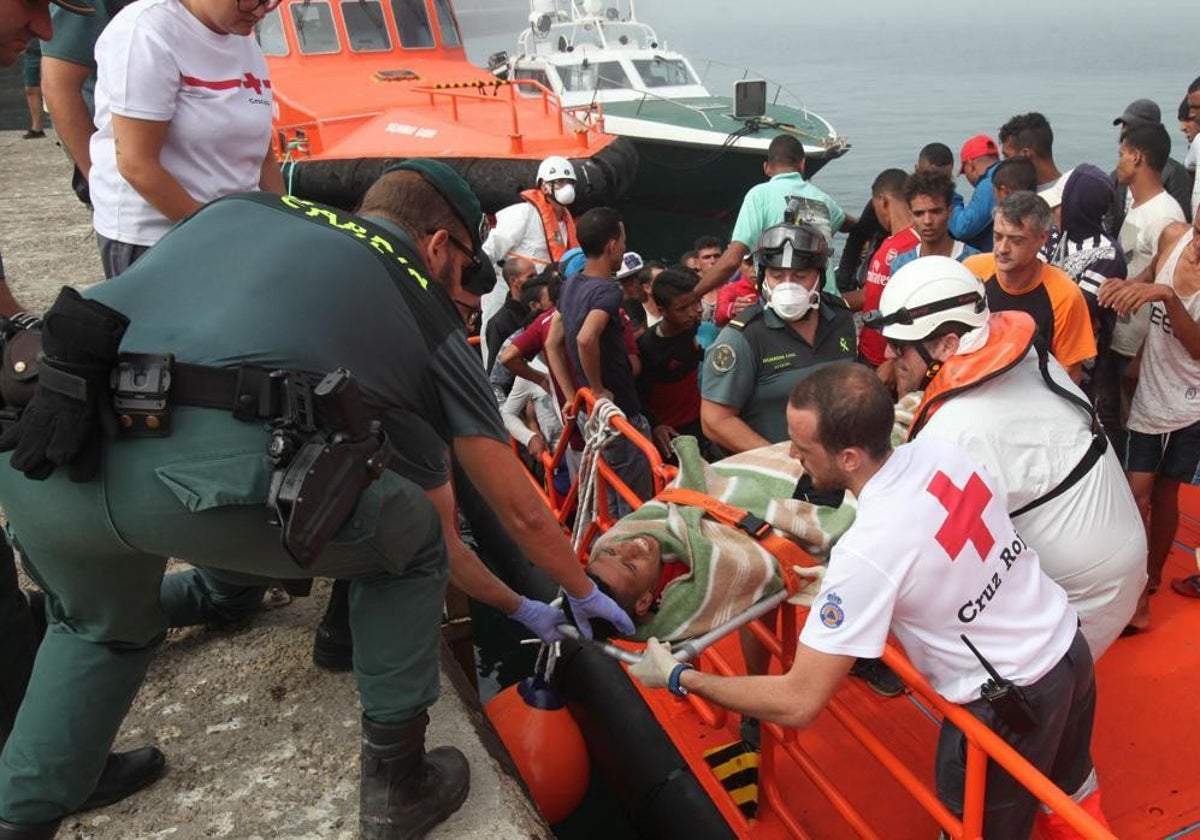 Agentes de la Guardia Civil y personal de Cruz Roja atiende a unos inmigrantes rescatados del mar