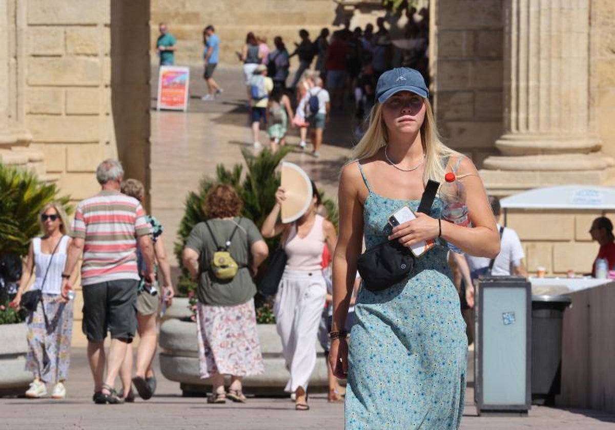 Un turista cruza la Puerta del Puente con una botella de agua en ola de calor en Córdoba