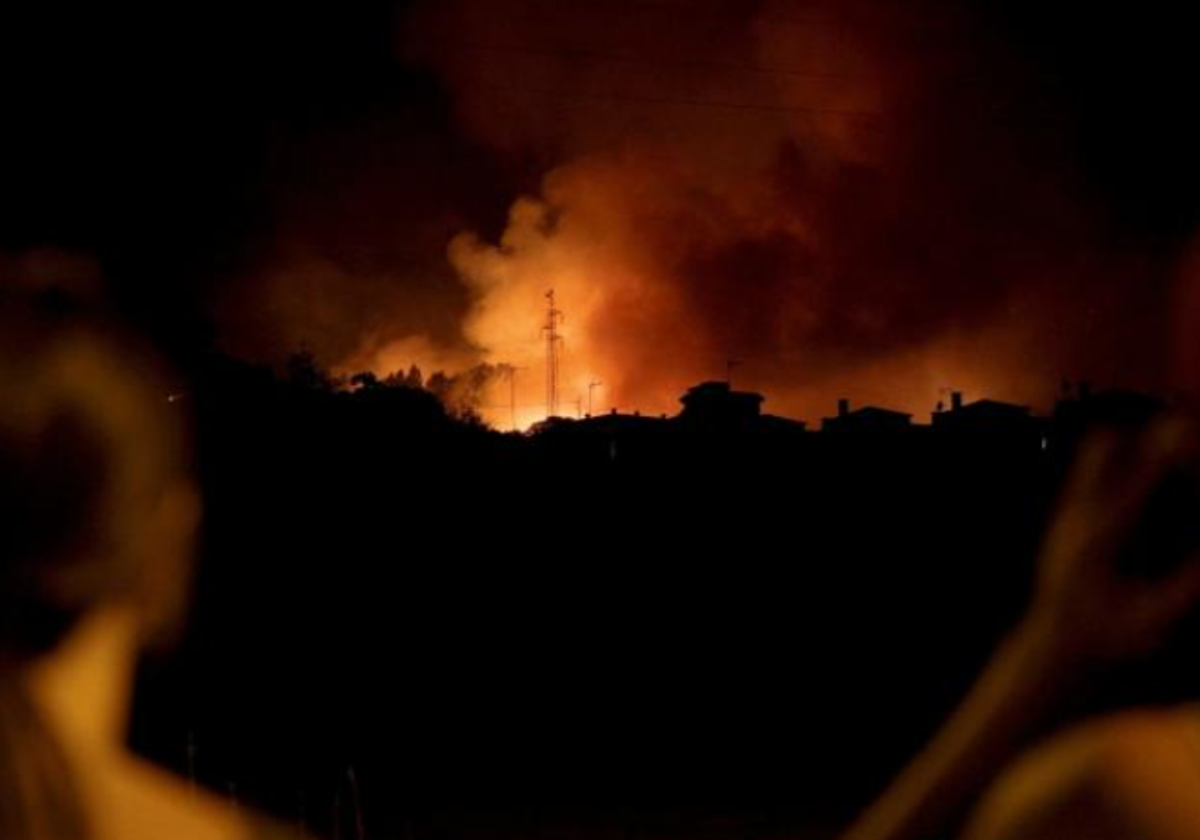 Dos vecinas observan el incendio, visible a kilómetros durante la noche