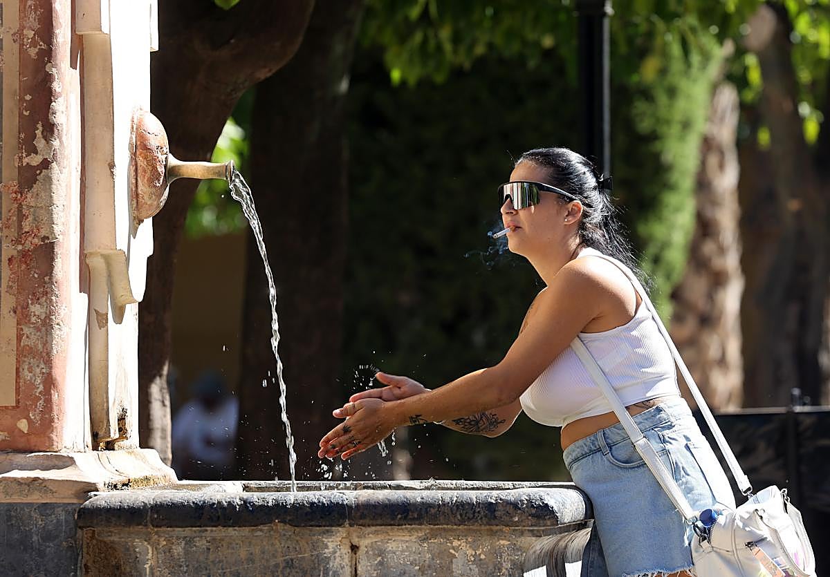 Una turista se refresca en el patio de los Naranjos de la Mezquita-Catedral