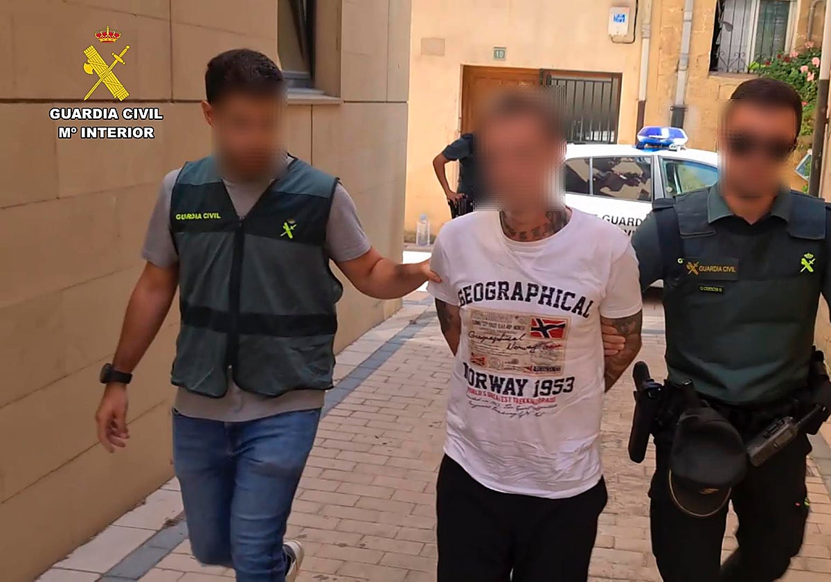 Dos agentes trasladan a uno de los detenidos por el crimen del empresario