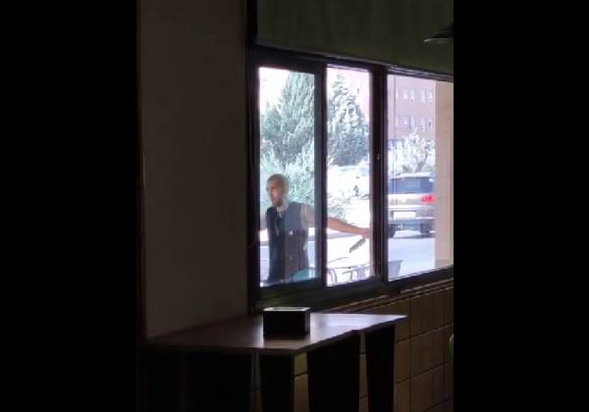 El joven a través de la ventana de un bar, donde se ve uno de los dos cuchillos que esgrimía