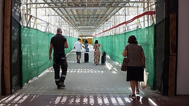 Viajeros atravesando la pasarela que conecta con el apartamiento de taxis