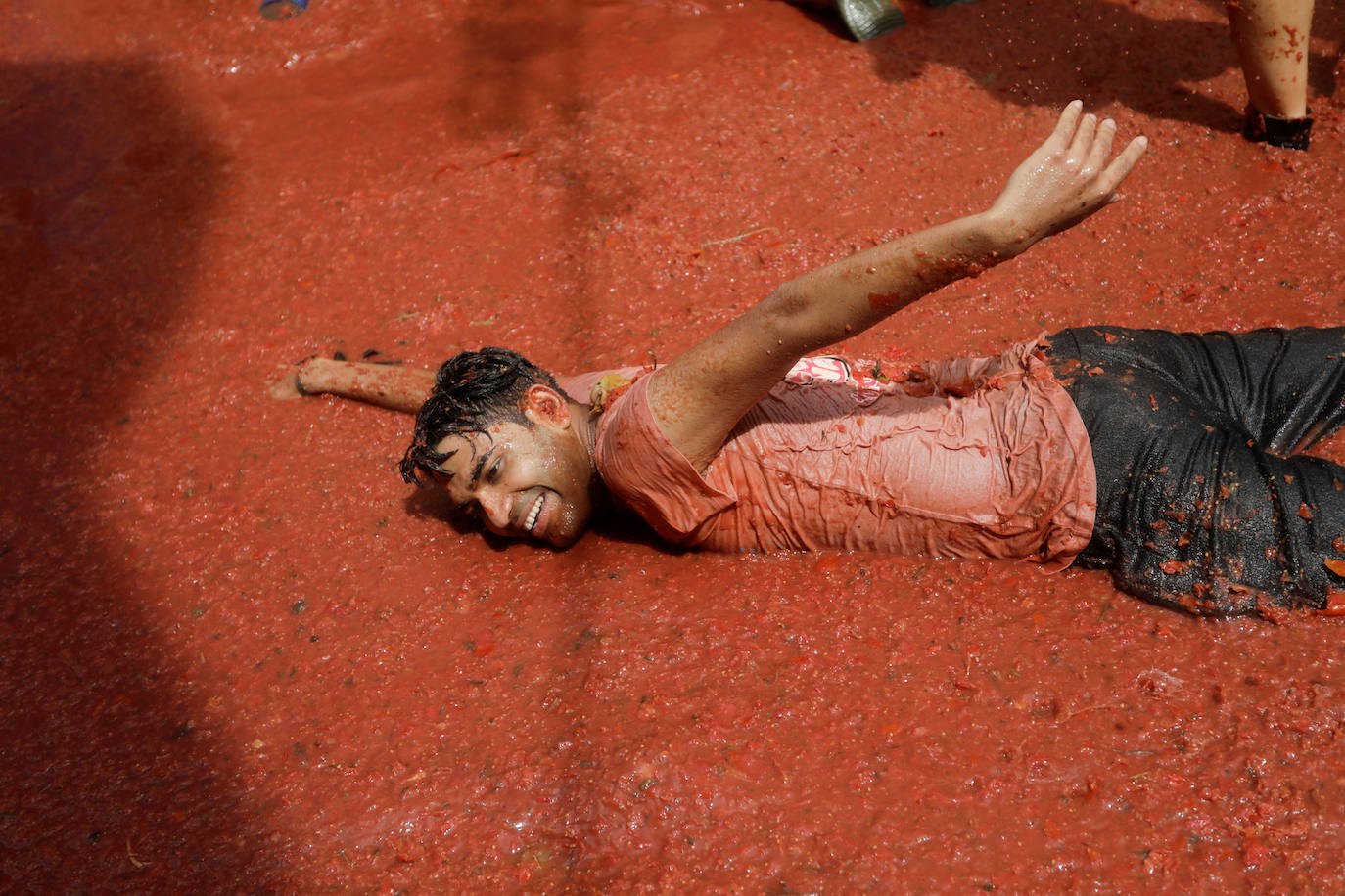 Un joven 'nada' en el suelo totalmente cubierto por tomate triturado