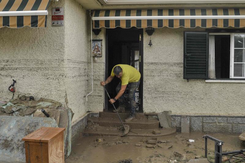 Un vecino intenta apartar el barro en las puertas de su casa en Aldea del Fresno