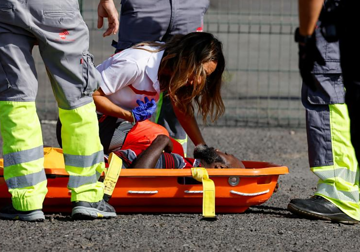 Una sanitaria atiende a uno de los migrantes rescatados hoy en el muelle de Arguineguín