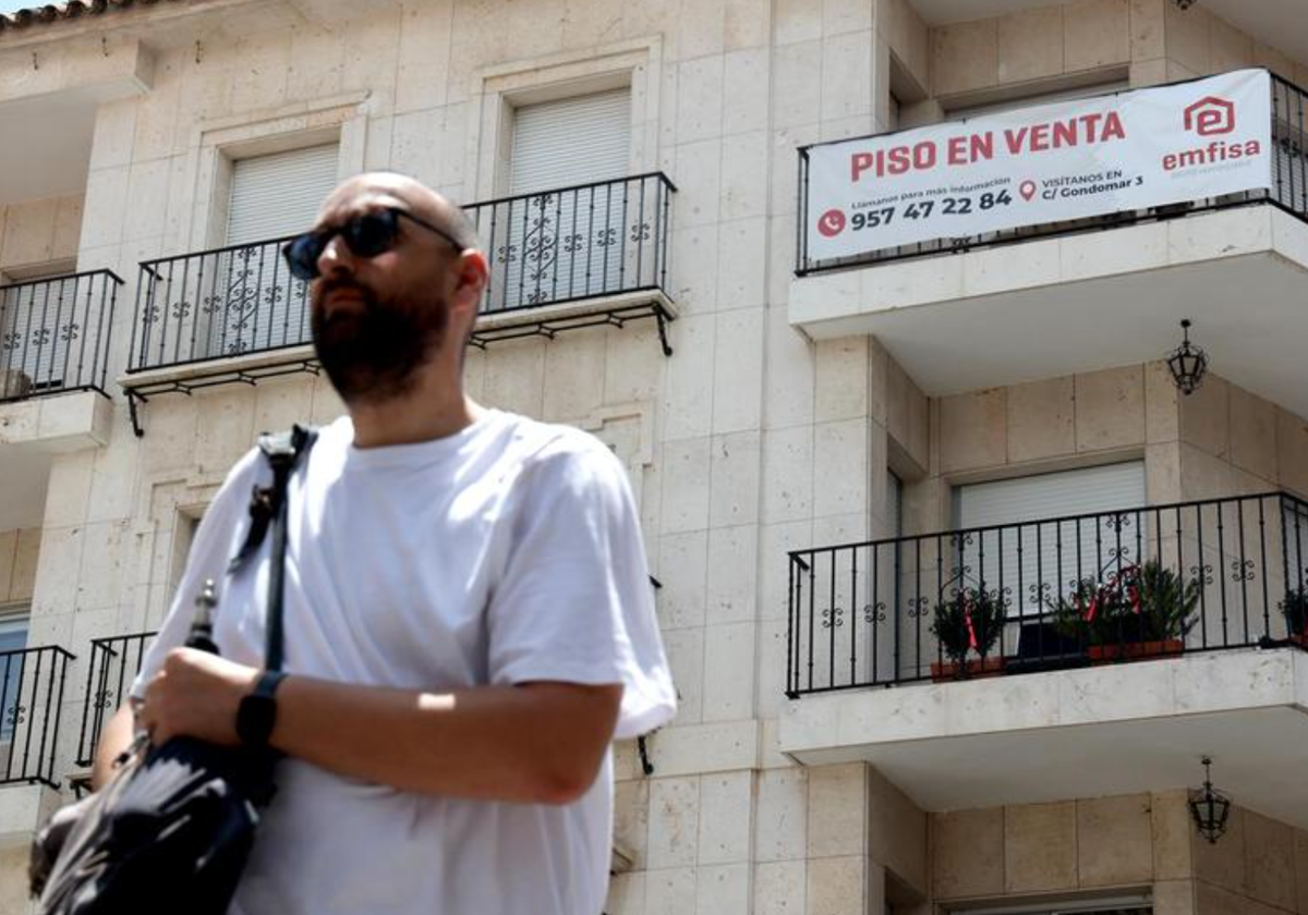 Un hombre pasa delante de un edificio con una vivienda en venta