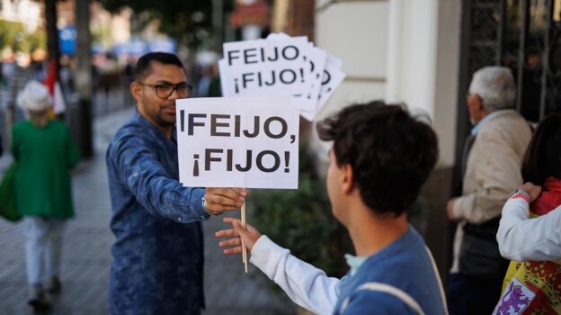 Dos personas sostienen pancartas que hacen referencia al líder del PP y candidato a la Presidencia del Gobierno, Alberto Núñez Feijóo