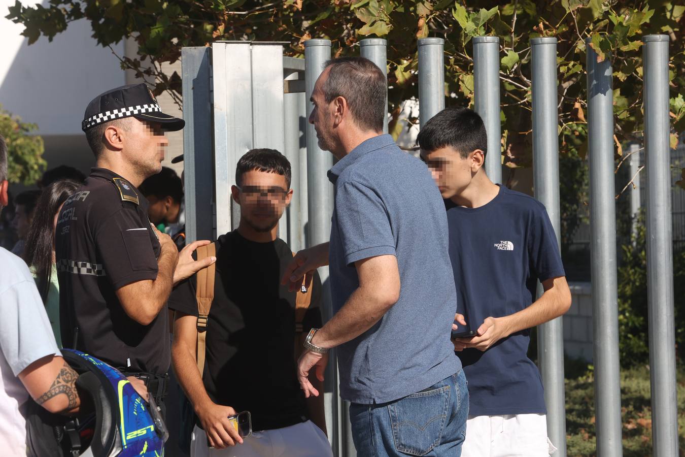 Un hombre habla con un agente de Policía, a la salida de unos alumnos del Instituto de Educación Secundaria (IES) Elena García Armada de Jerez de la Frontera (Cádiz)