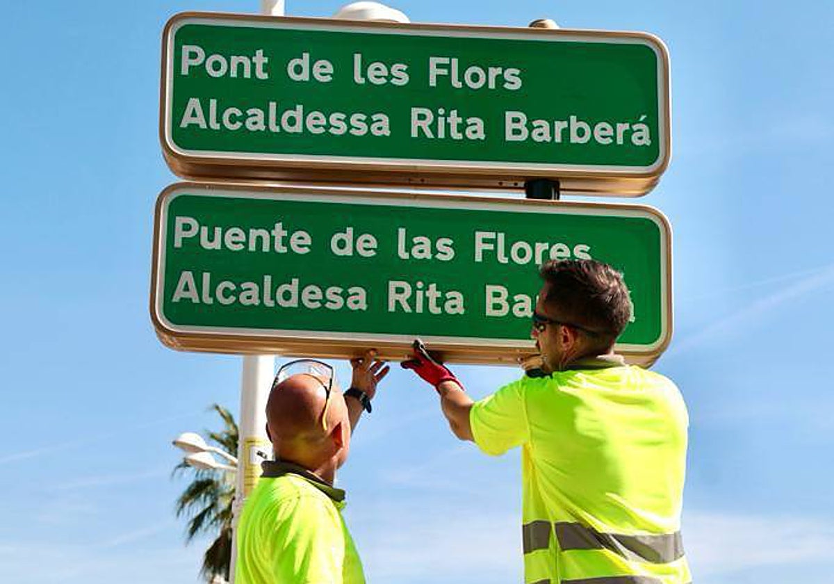 Imagen de los operarios municipales colocando el letrero sobre el Puente de las Flores este jueves en Valencia