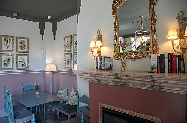 El espejo, sobre la chimenea y libros, en la zona del restaurante