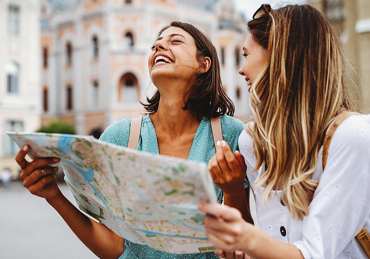 Dos jóvenes buscan en un mapa una calle en concreto