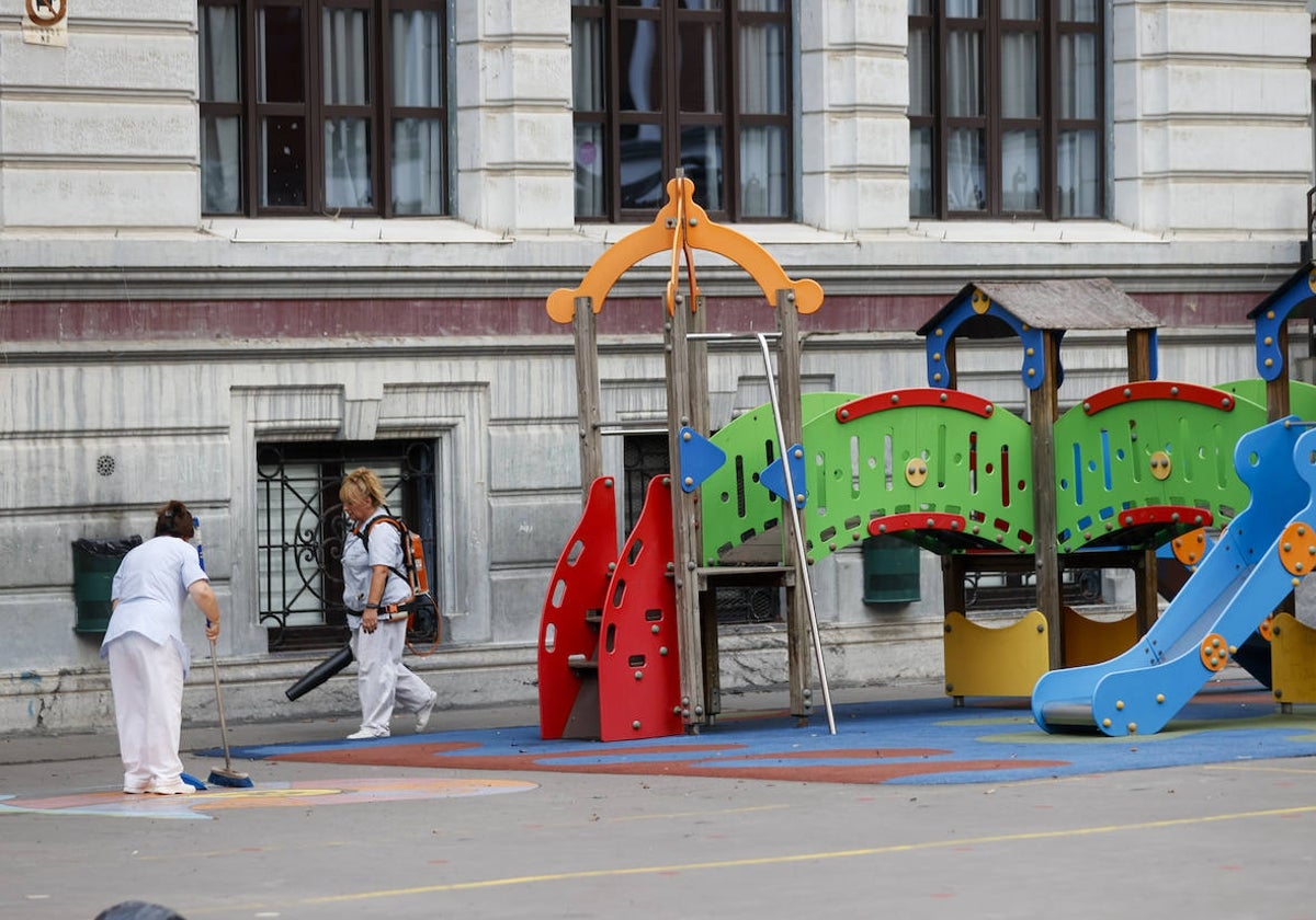 Dos empleadas realizan labores de limpieza en el patio de un colegio de Bilbao
