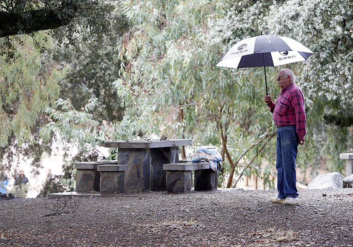 Un hombre usa su paraguas frente a un perol en Los Villares