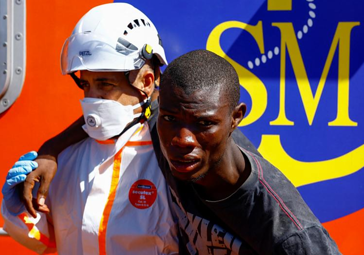 Un rescatador ayuda a un migrante en su desembarco en el muelle de Arguineguín, Gran Canaria