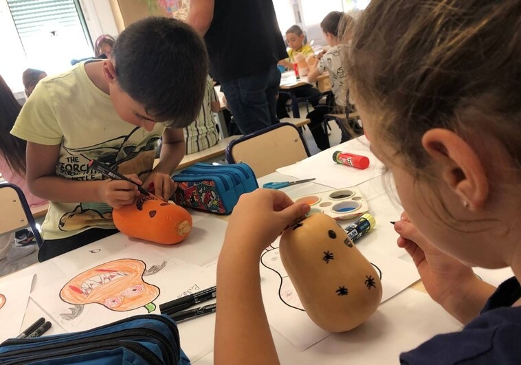 Imagen de dos niños decorando calabazas de cacahuete españolas para Halloween