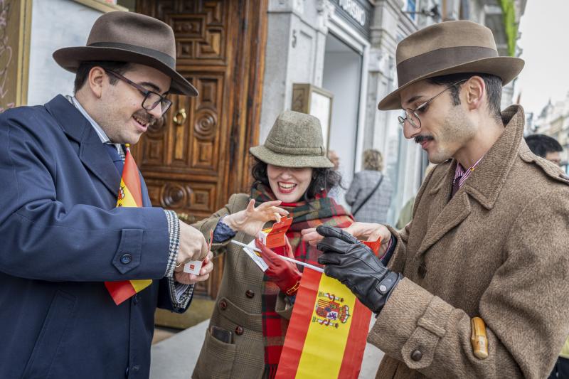 Tres personas vestidas para la ocasión se comen un pastelito conmemorativo repartido en Madrid