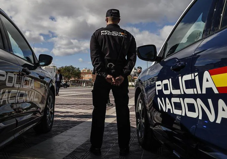 Dos coches de la Policía Nacional junto a un agente