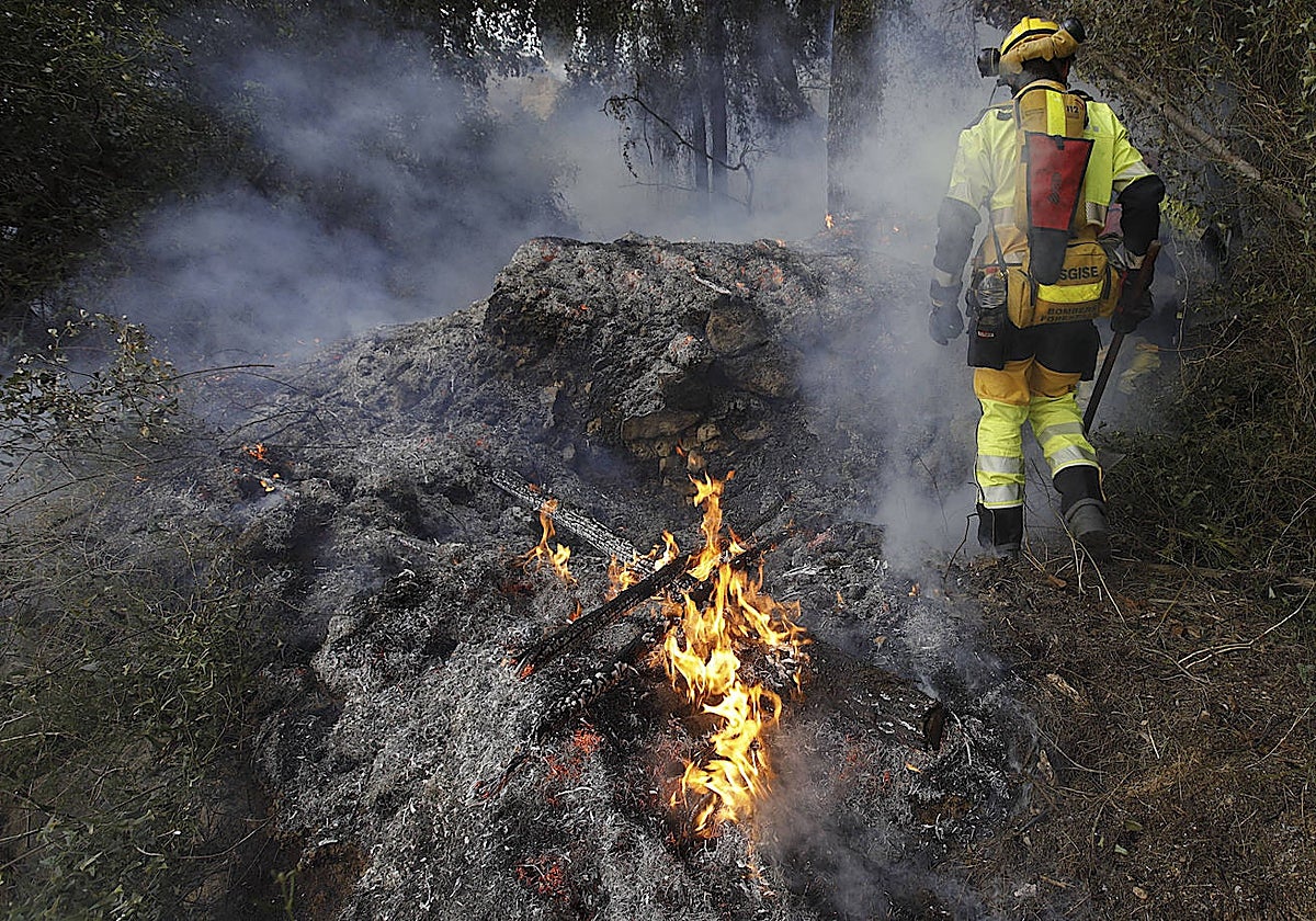 Imagen de un bombero en los trabajos de extinción del incendio de Montitxelvo (Valencia). En el vídeo, desalojo de algunos vecinos del término de Ador este sábado por parte de la Guardia Civil