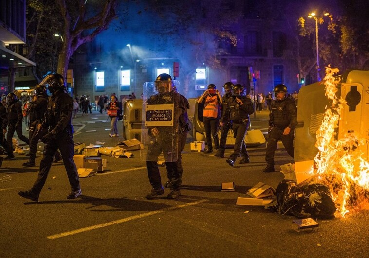 Antidisturbios pasan delante de contenedores quemados durante una manifestación por el referéndum del 1-O en Cataluña
