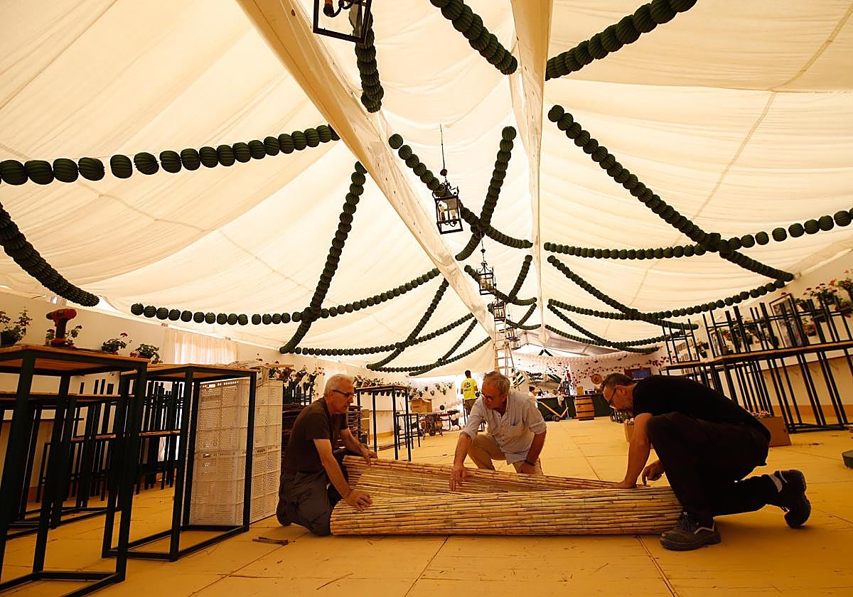 Varias personas trabajan en el montaje de una caseta en mayo de 2022