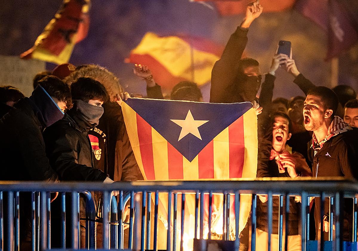 Decenas de manifestantes queman una bandera estelada durante una manifestación contra la amnistía frente a la sede del PSOE en Ferraz