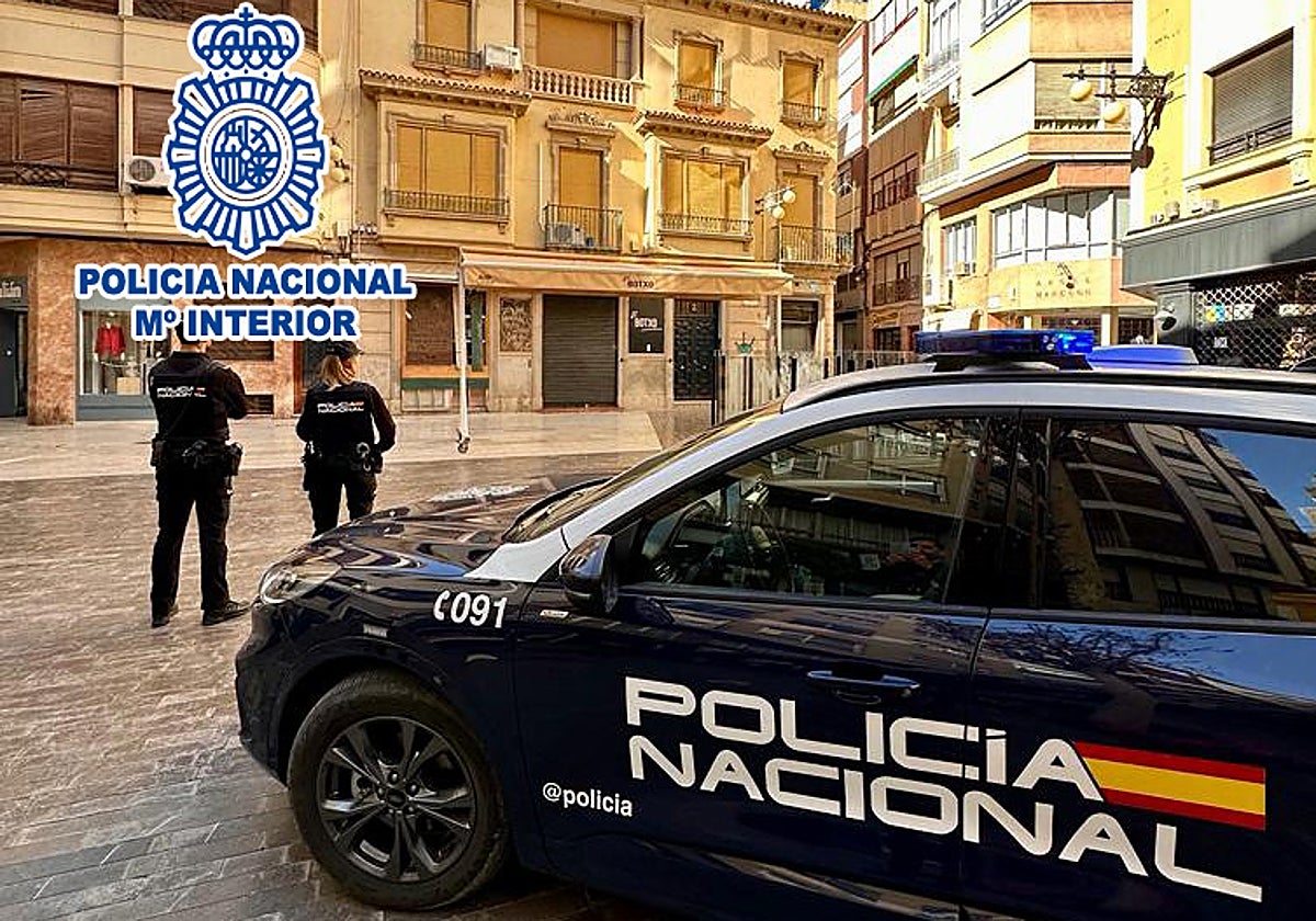 Dos agentes de la Policía Nacional junto a un coche patrulla en Elche.