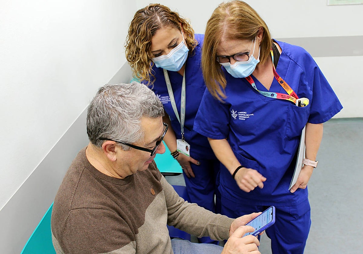 Imagen de dos enfermeras del Hospital General de Valencia junto a un paciente con la app 'Painkey'