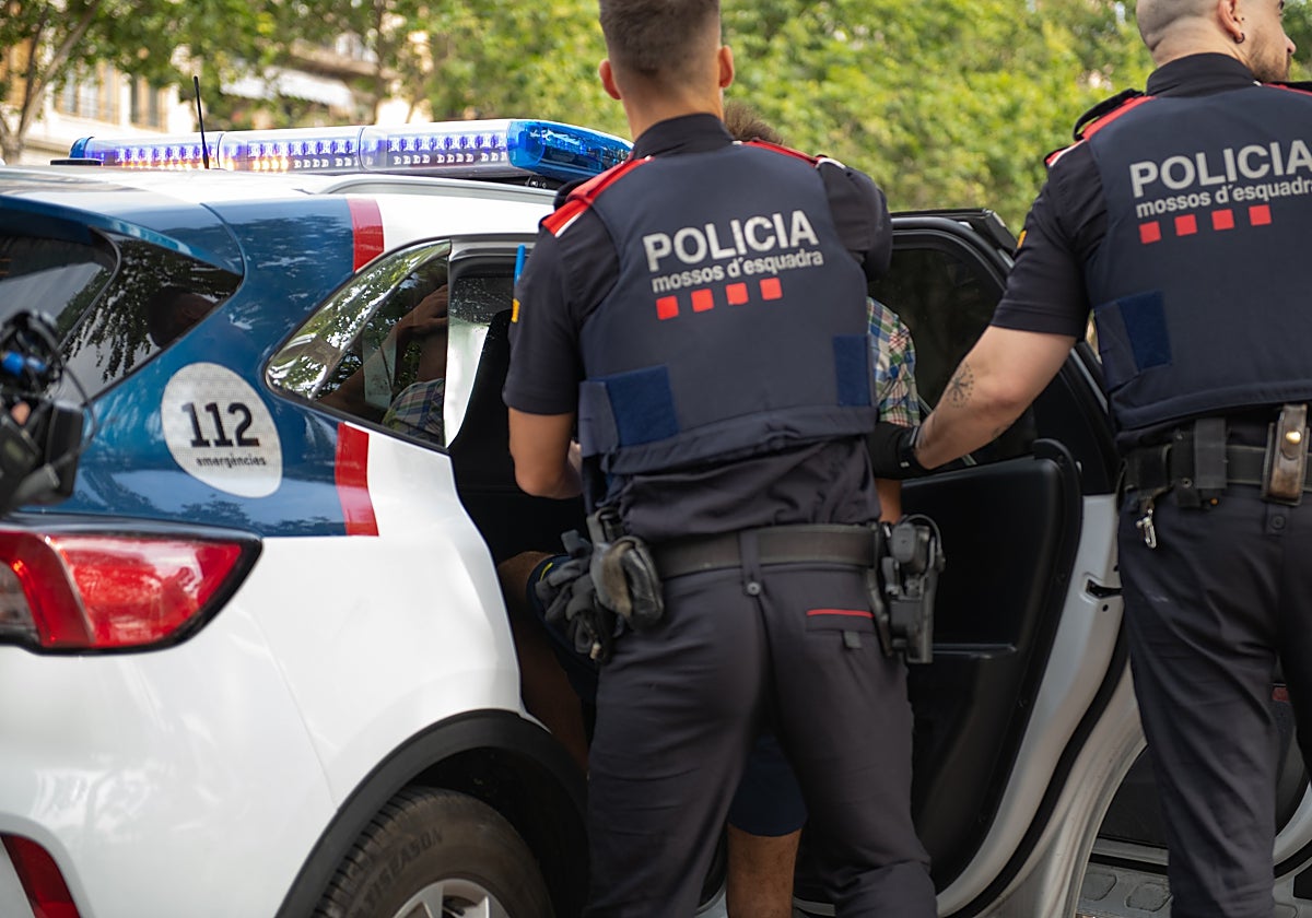 Agentes durante el traslado de un detenido en un coche patrulla