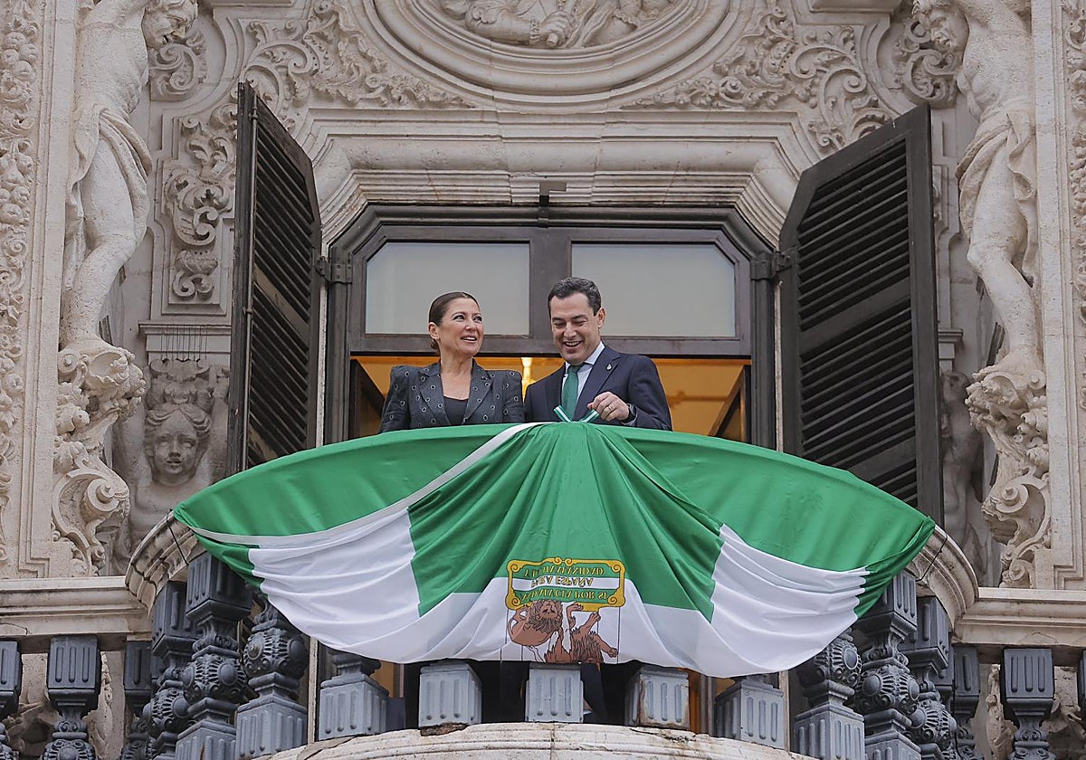 El presidente de la Junta, Juanma Moreno, despliega este lunes la bandera sobre la puerta principal de San Telmo en presencia de la bailaora Sara Baras