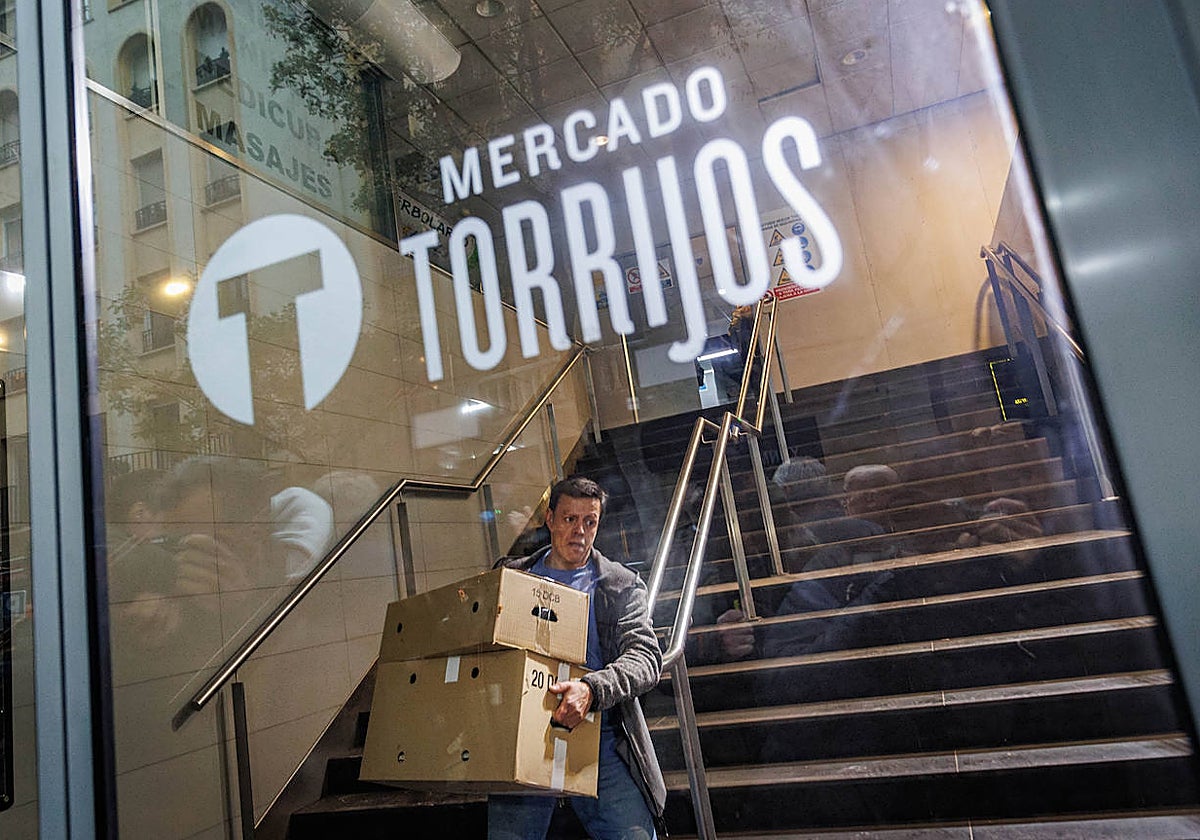 David López, dueño de uno de los puestos, carga dos cajas tras encontrarse su puesto tapiado