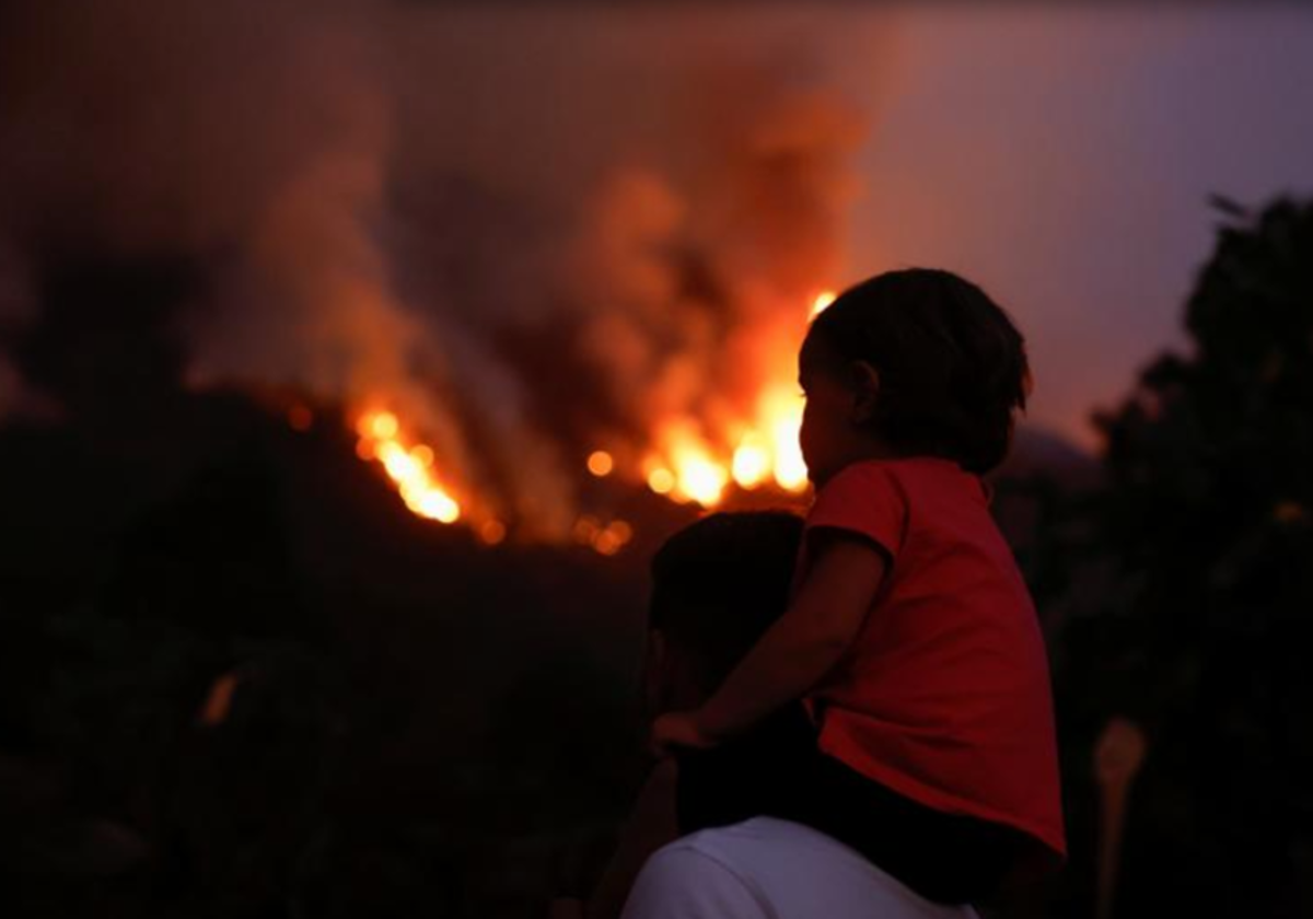 Un niño observa el incendio de Tenerife subido a hombros