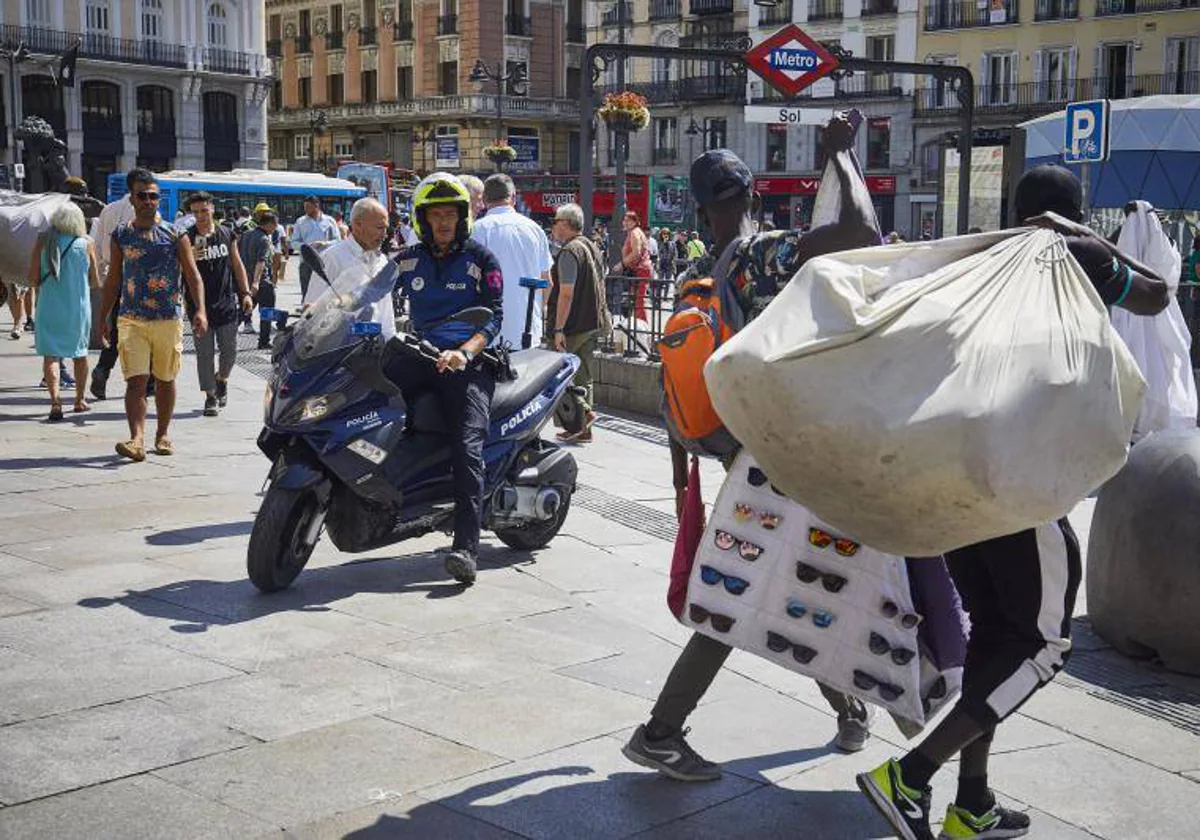 Los manteros intentan vender sus productos bajo la vigilancia de la Policía Municipal