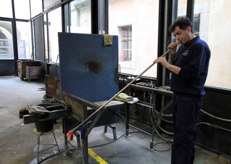 Imagen secundaria 1 - En Real Fábrica de Cristales realizan un trabajo coordinado y en equipo. Arriba, Raquel talla una copa que ha salido del taller de soplado, donde Juanjo (abajo) y sopla por la caña de acero para hacer la primera 'burbuja' al vidrio. A la dererecha, Diego sopla mientras José sujeta el molde para dar la forma