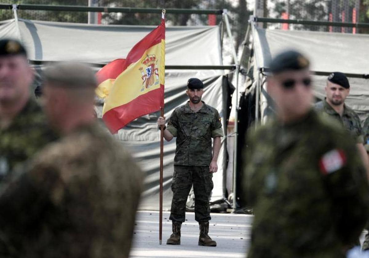 Un soldado español sostiene la bandena española en la base militar de Adazi, Letonia. Imagen de archivo