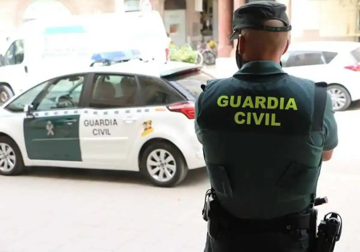 Imagen de archivo de un guardia civil frente al coche patrulla