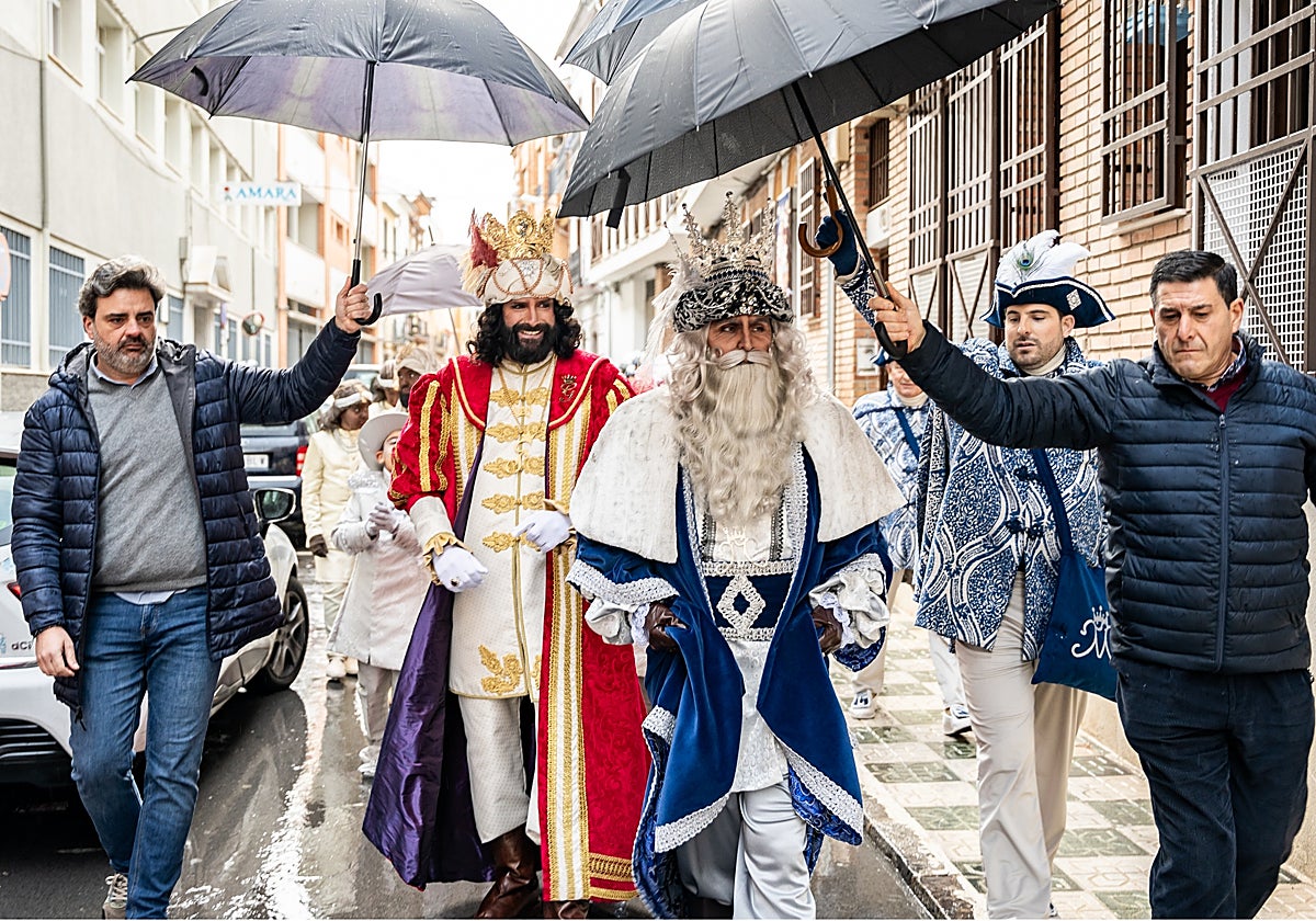 Los Reyes magos en Lucena bajo paraguas ante una lluvia fina al principio de la mañana
