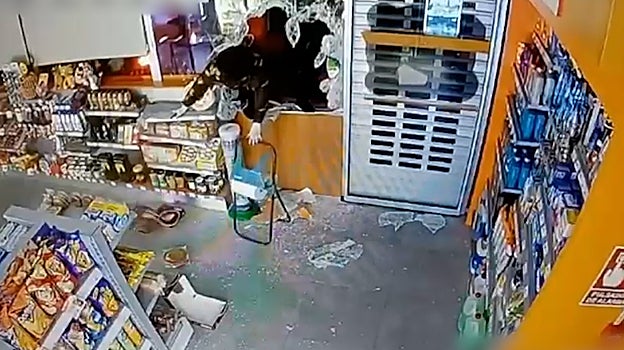 Uno de los malhechores entra en una tienda a través de un cristal roto